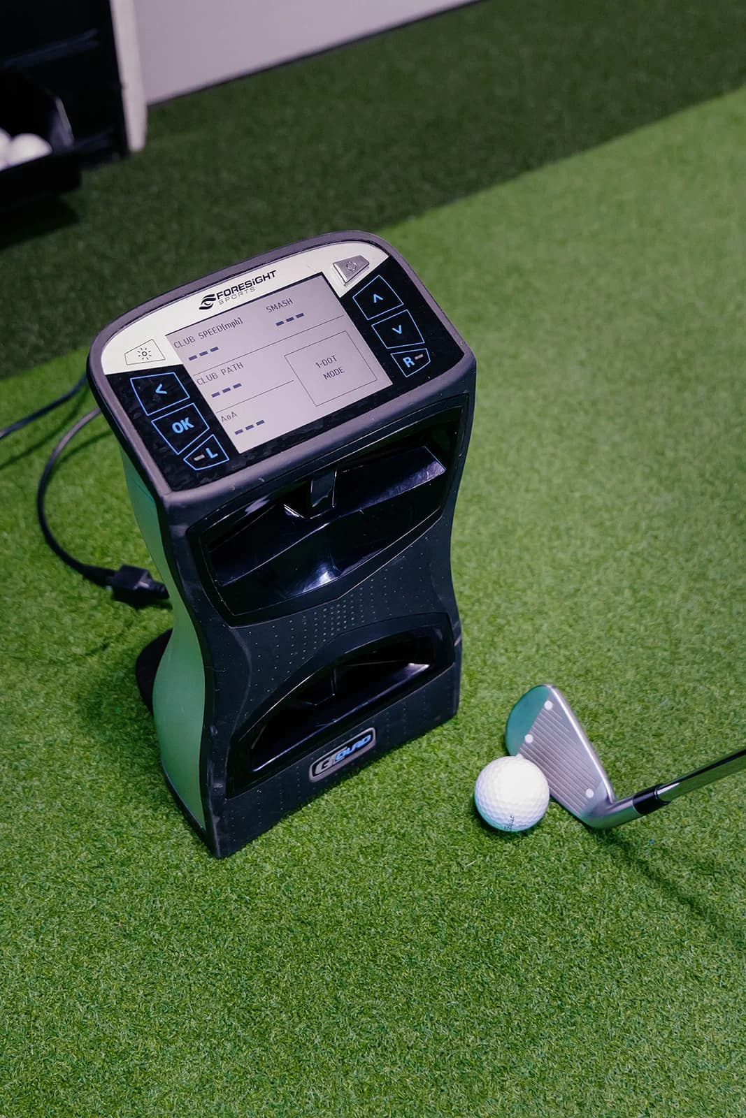 The Foresight GC Quad launch monitor on the studio floor beside a ball and an iron