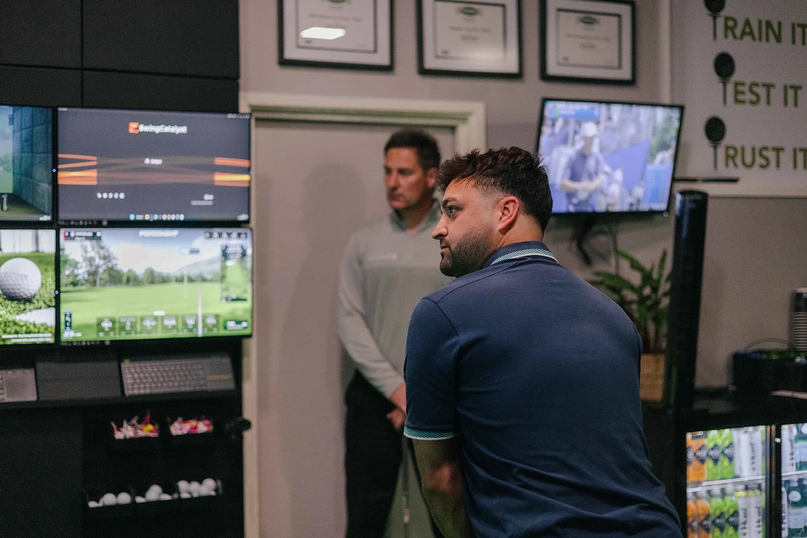 A coach and pupil looking over swing video and launch data on the studio screens