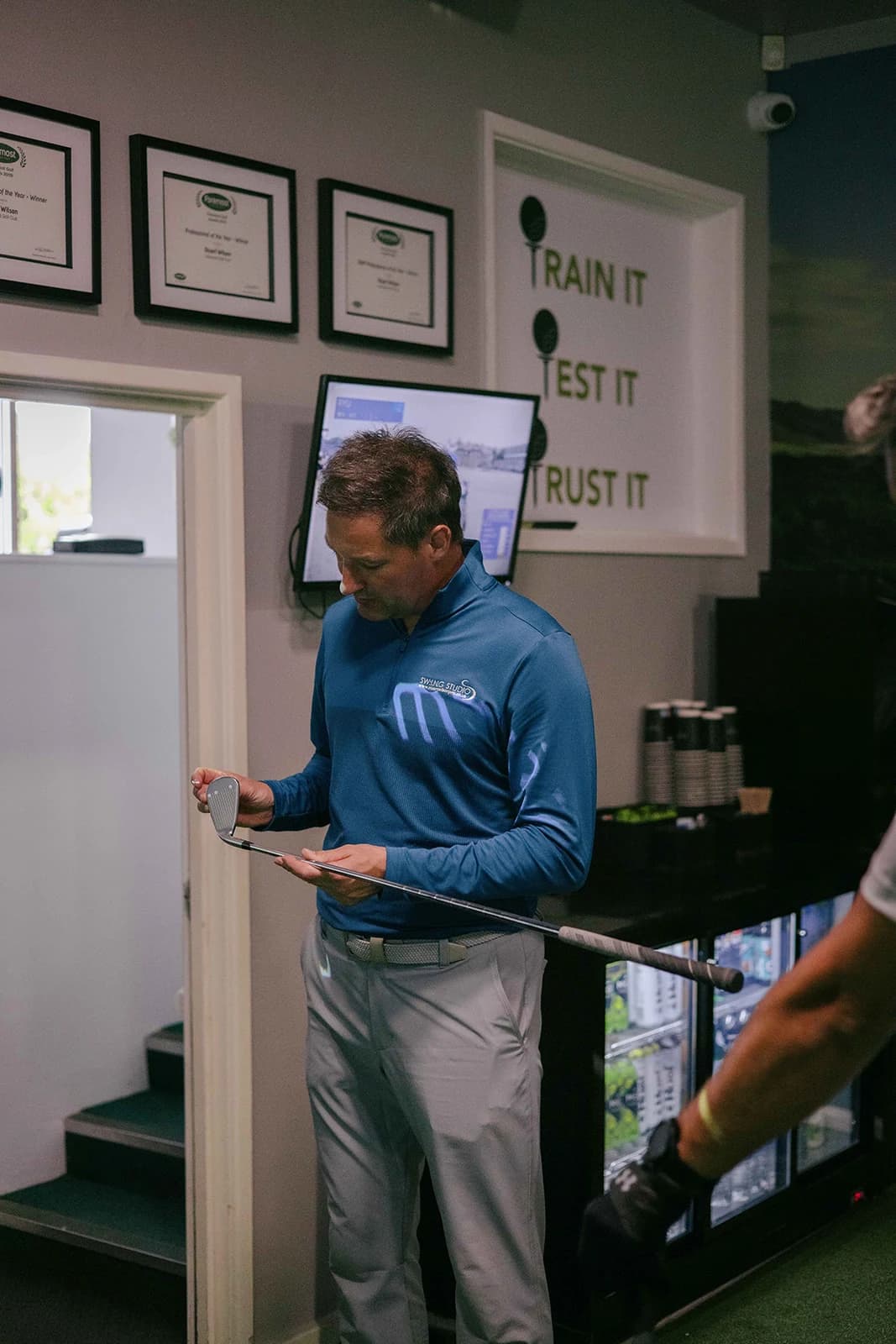 Stuart Wilson, PGA Professional, looking over a club at the entrance to SW:ING Studio