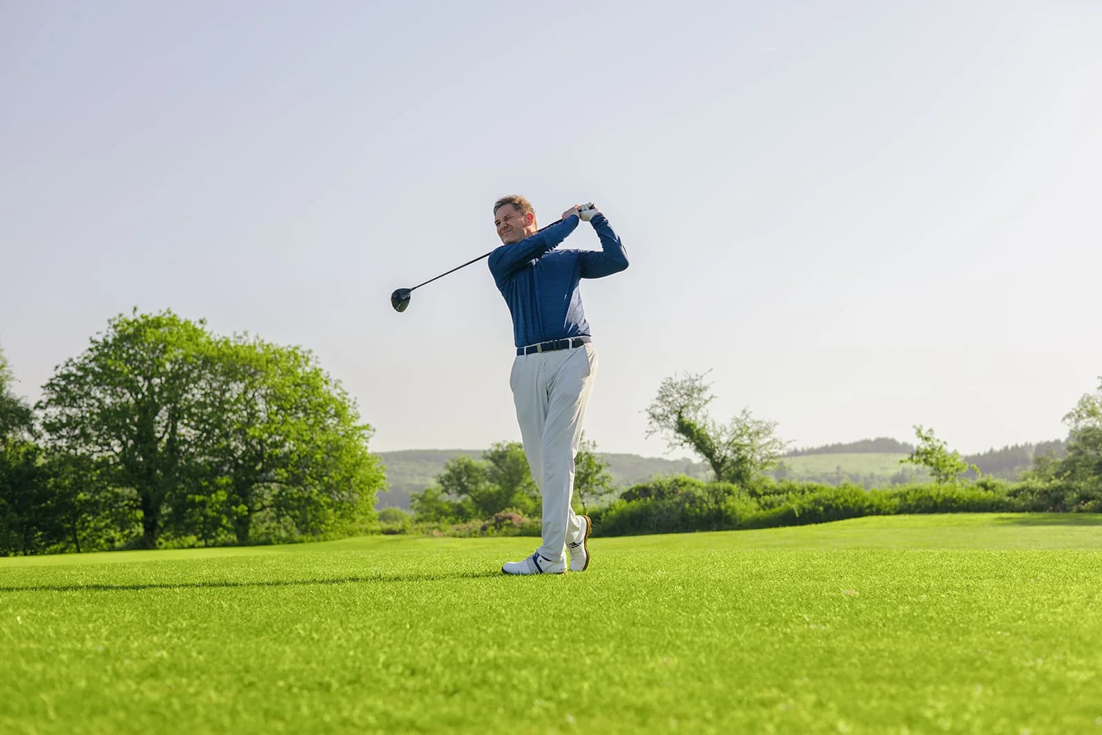 Stuart Wilson holding his finish after a driver swing, seen from a low angle on the fairway